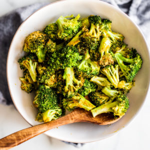 White serving bowl full of cooked broccoli florets.