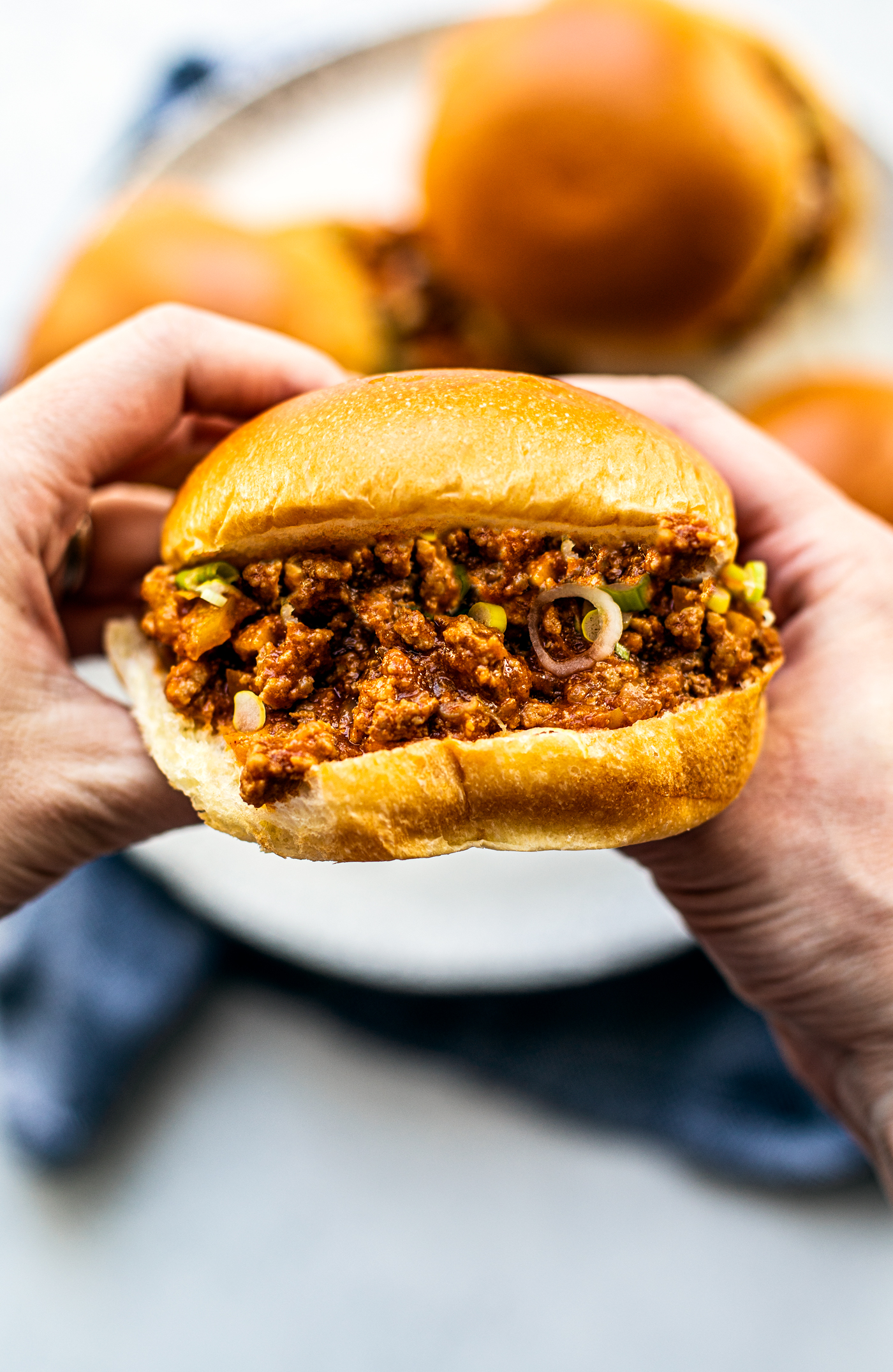 Two hands holding up a full Sloppy Joe.
