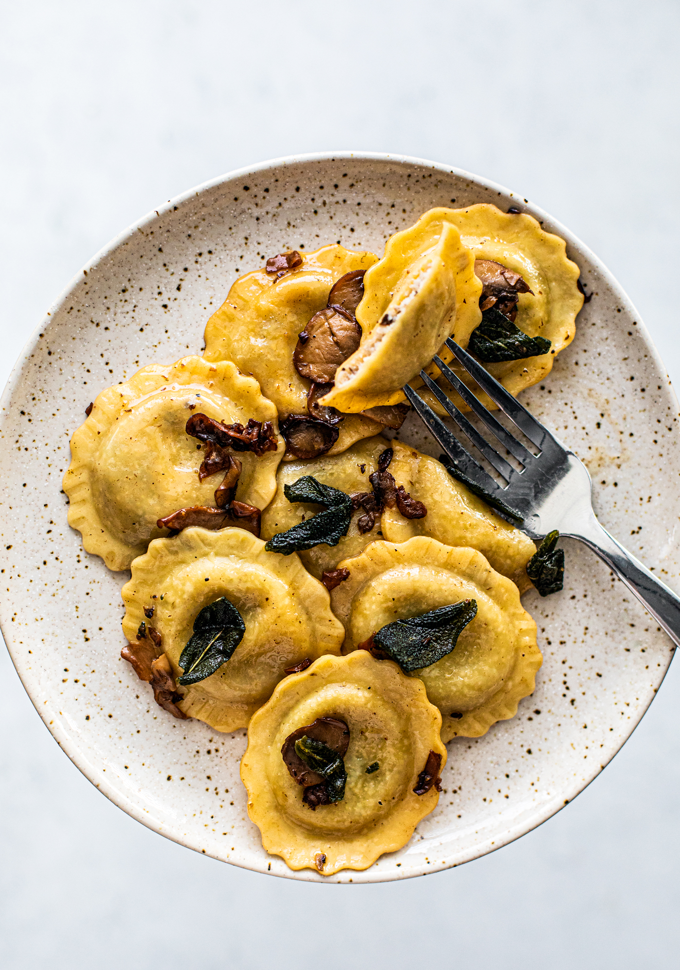 Plate of mushroom ravioli with a fork.