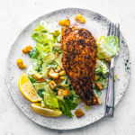 Speckled stone plate with caesar salad topped with a fillet of salmon.