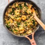 Pan full of dirty rice and shrimp, garnished with fresh parsley.