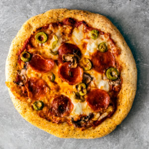 Golden crisp pizza with cheese, pepperoni, olives, and mushrooms.