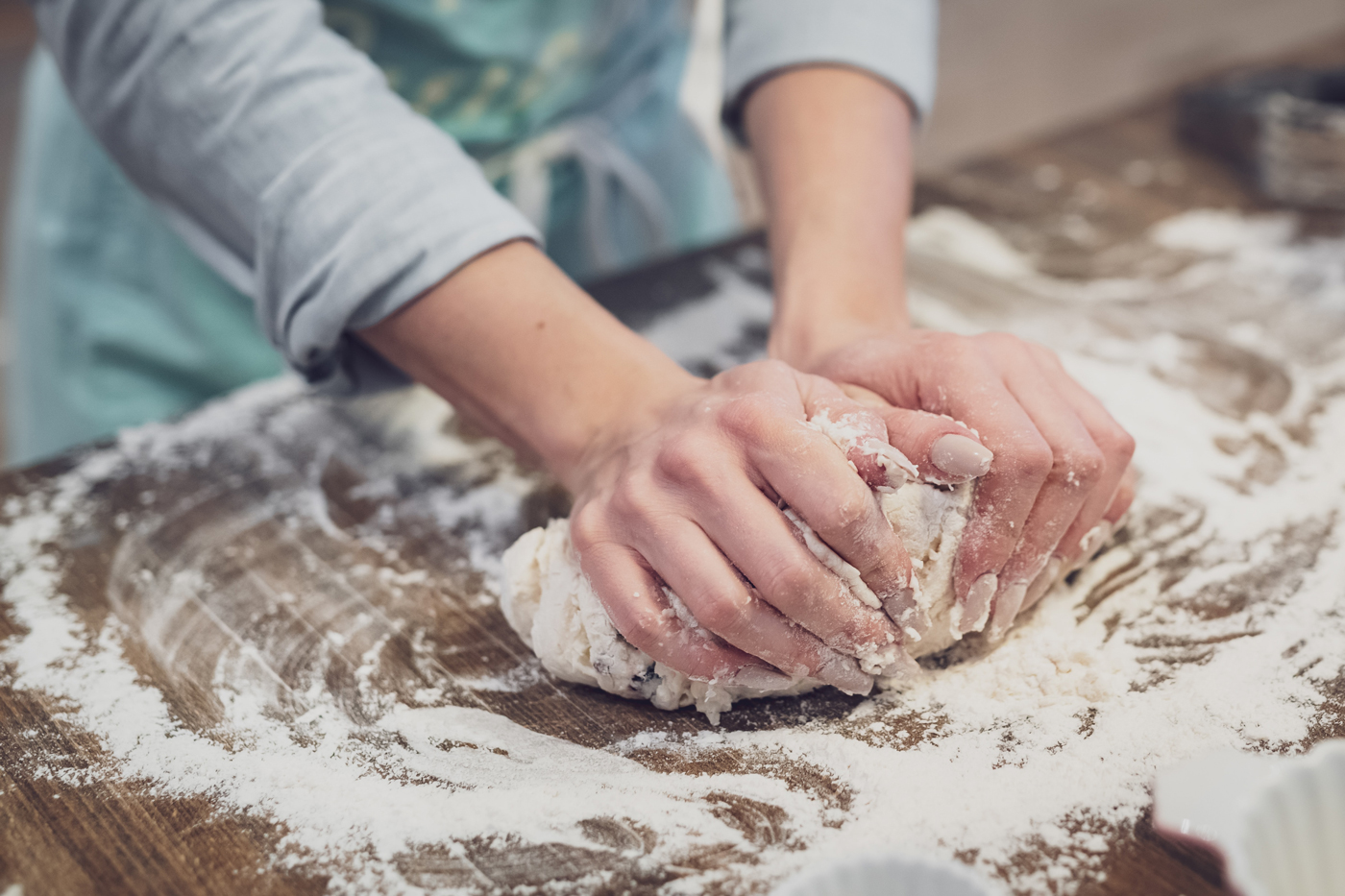 Hands rolling dough in flour.
