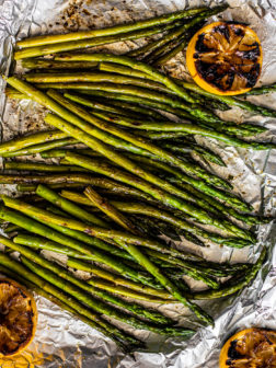Grilled asparagus on tin foil with charred lemons.