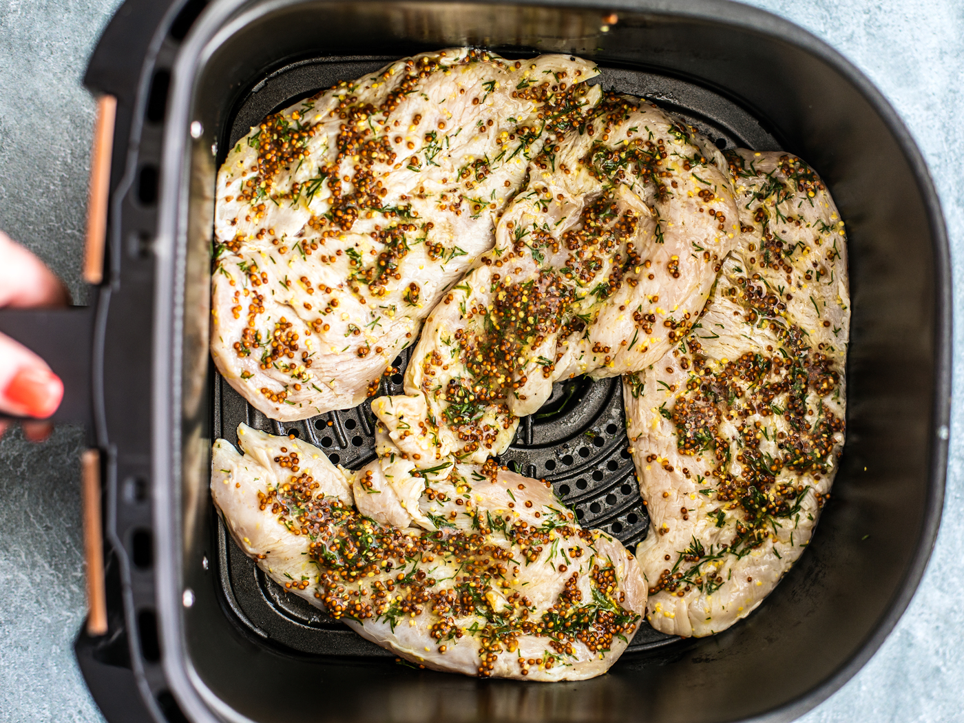Marinated chicken breasts in air fryer basket.