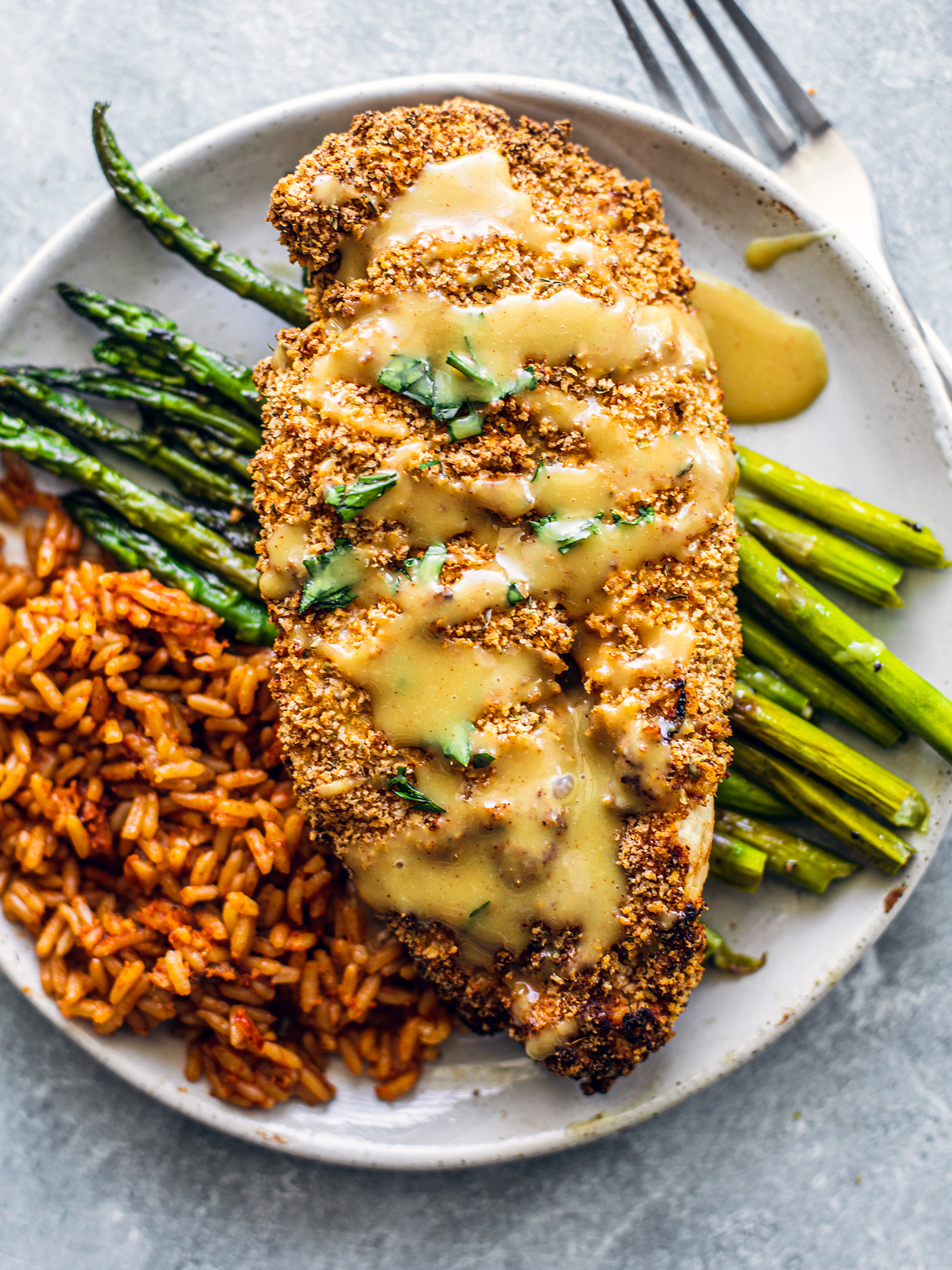 Crispy chicken cutlet on a bed of red rice and asparagus.