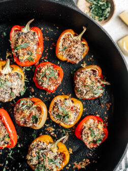 Cast iron pan with baked stuffed mini peppers covered in toasted breadcrumbs.
