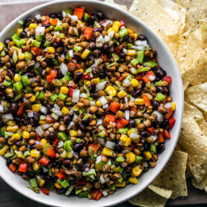 Close up of bowl of texas caviar with tortilla chips on the side of the bowl.