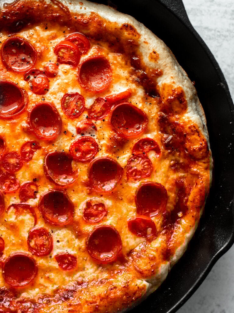 Close up of pizza in cast iron skillet.