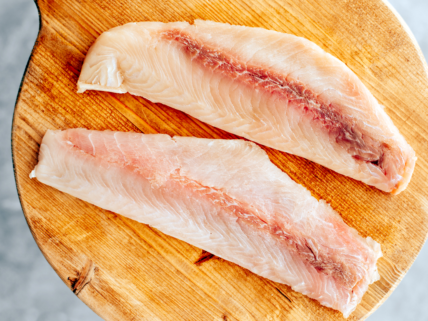 Close up of grouper fillets on a wooden cutting board.