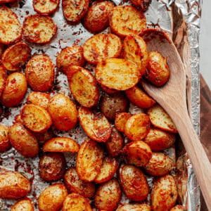 Baking sheet covered in foil with seasoned baby potatoes evenly spread out on top.