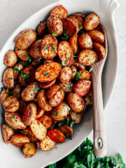 Serving platter of crispy potatoes garnished with parsley.