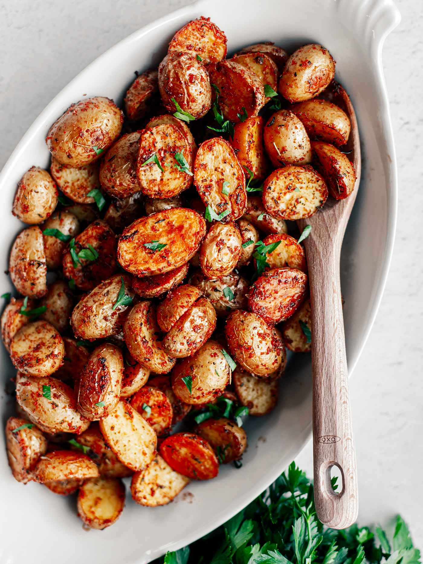 White serving dish full of crispy roasted potatoes.