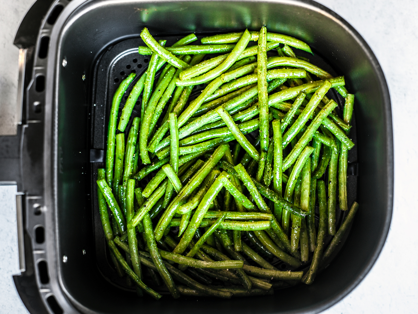 Green beans in air fryer basket.