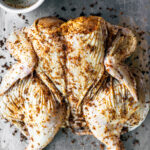 Spatchcocked chicken on a baking sheet.