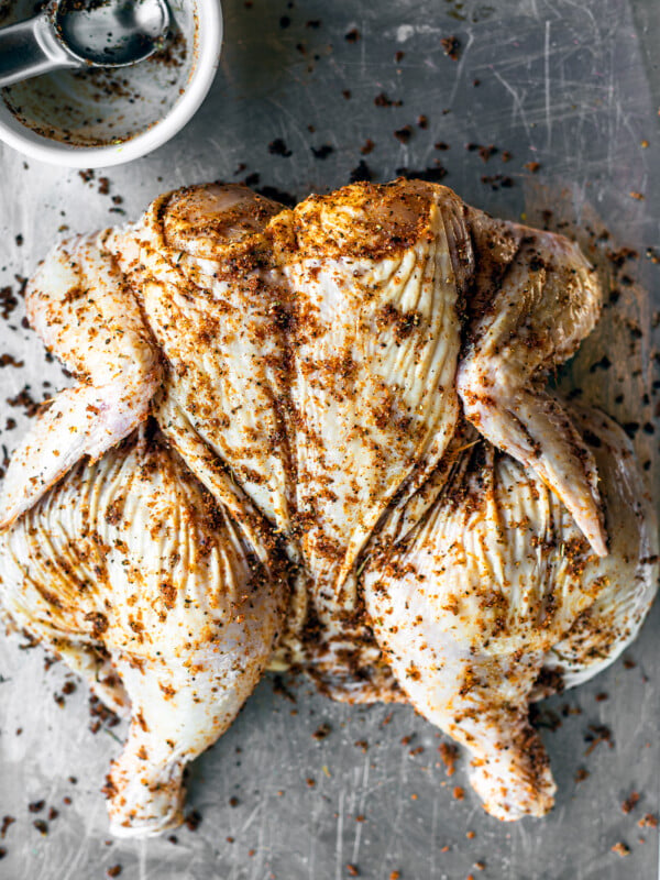 Spatchcocked chicken on a baking sheet.