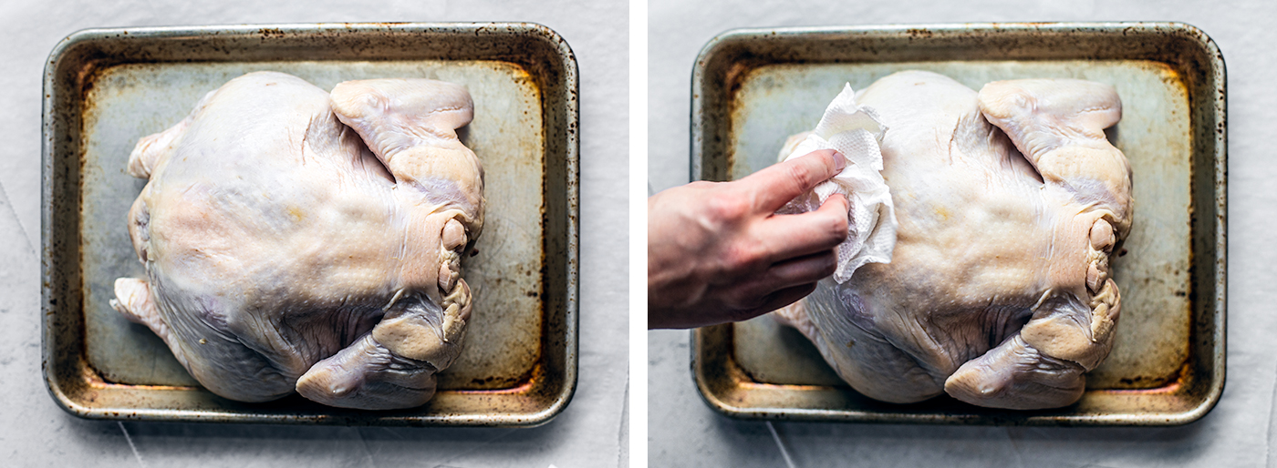 Baking sheet with whole chicken being pat dry with paper towels.