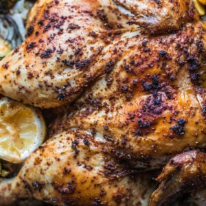 Spatchcocked chicken on baking sheet with veggies.
