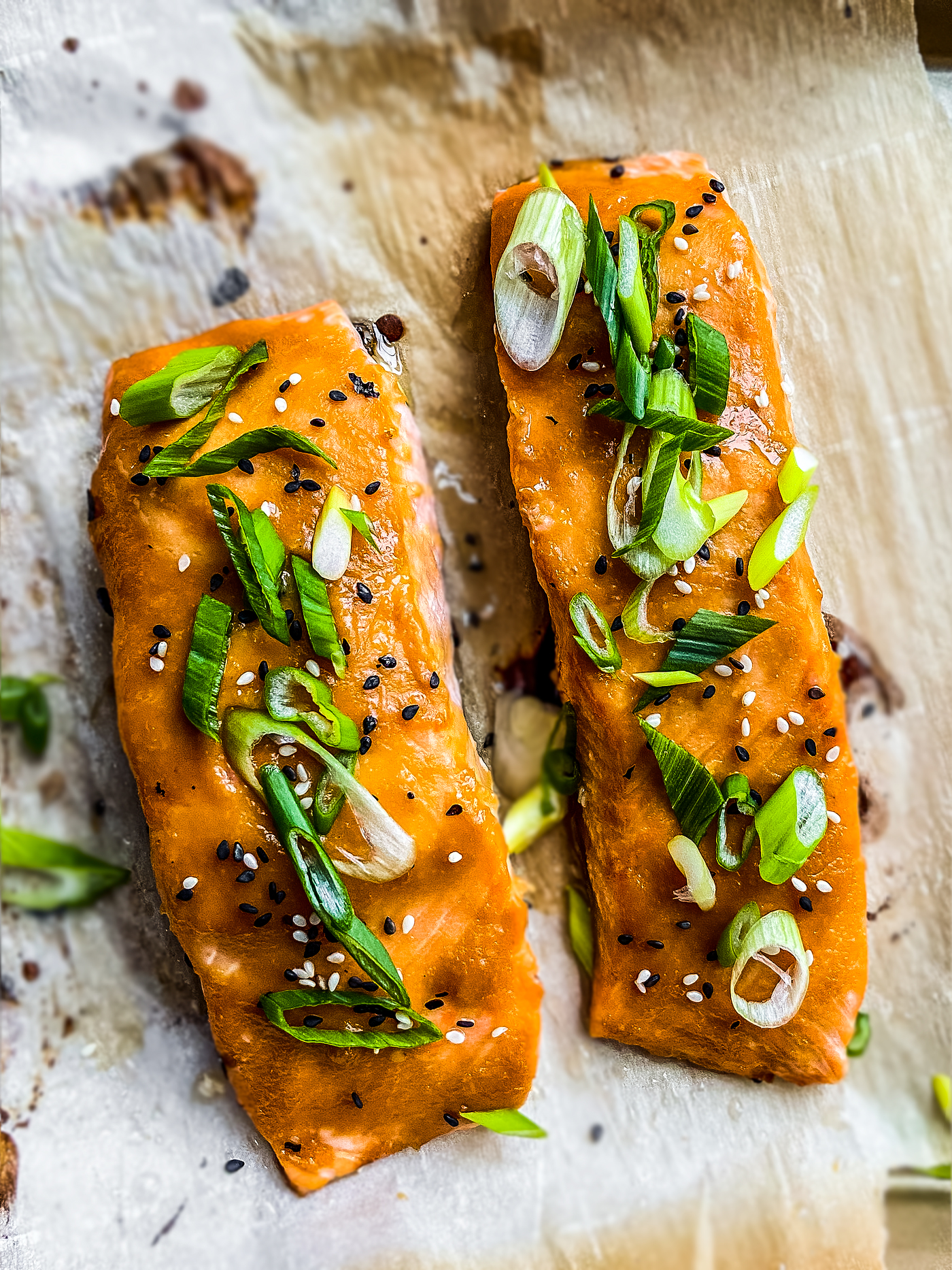 Two fillets of salmon glazed with miso and garnished with sesame seeds and scallions.