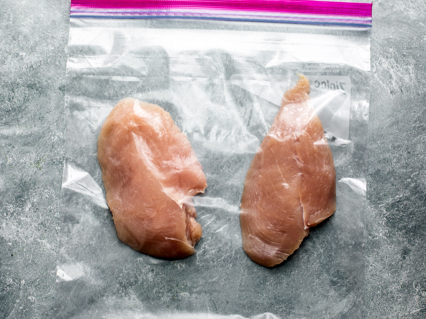 Raw chicken cutlets in freezer bag.