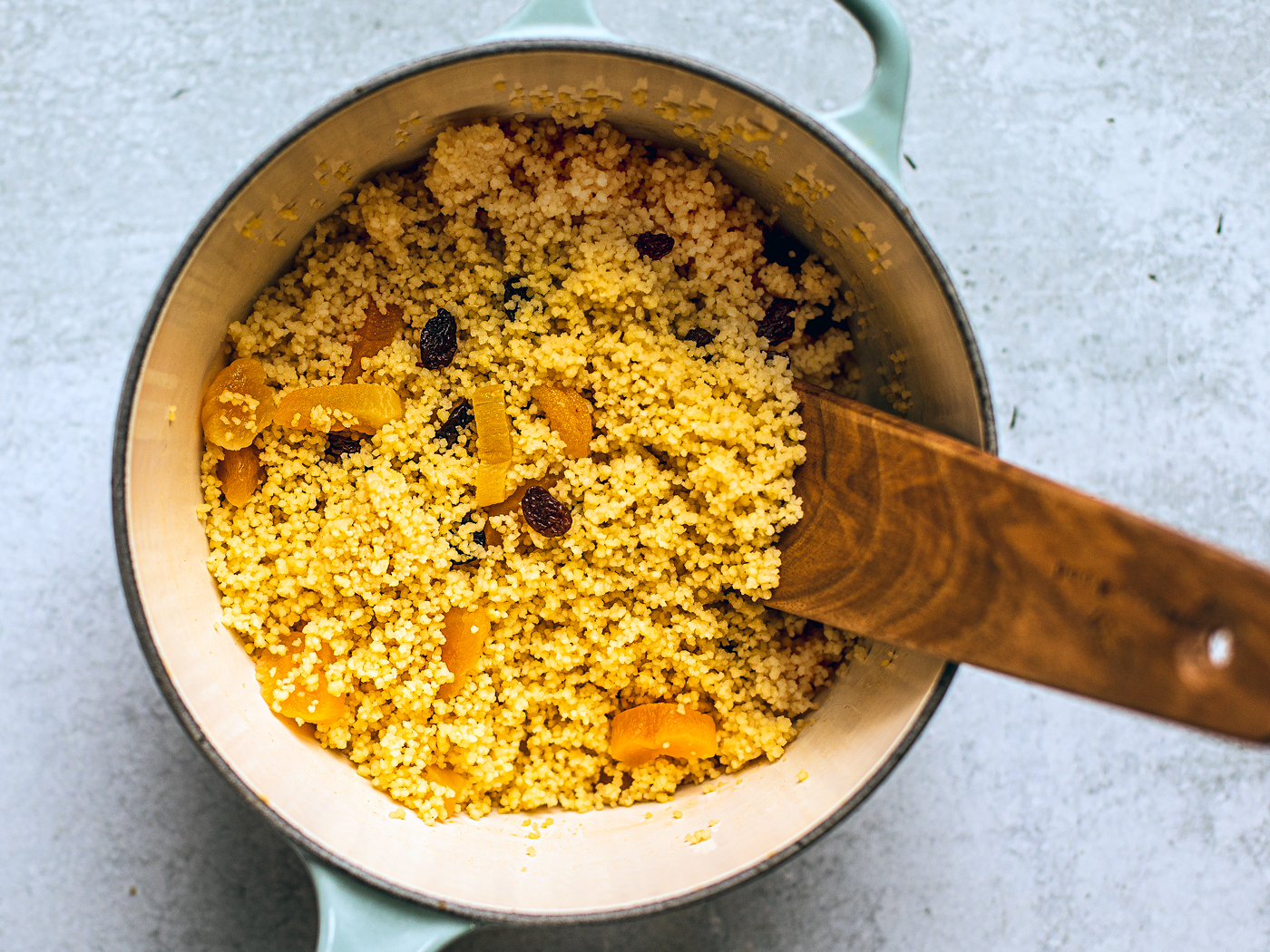 Small pot full of couscous, raisins, and apricots.