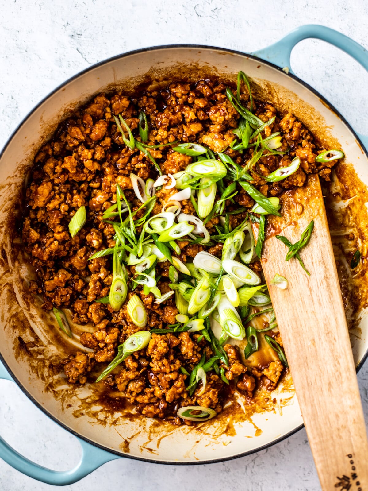 Braiser full of cooked hoisin sesame ground chicken and sliced scallions added.