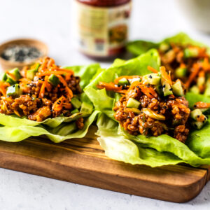 Side shot of two lettuce wraps on a wooden serving board.