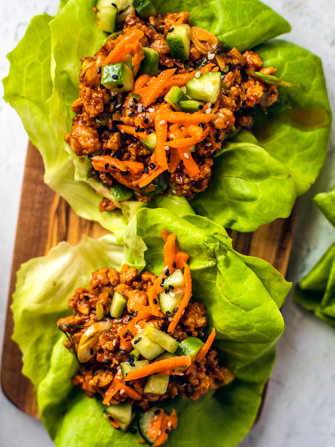 Close up of chicken lettuce wraps on a wooden serving board.