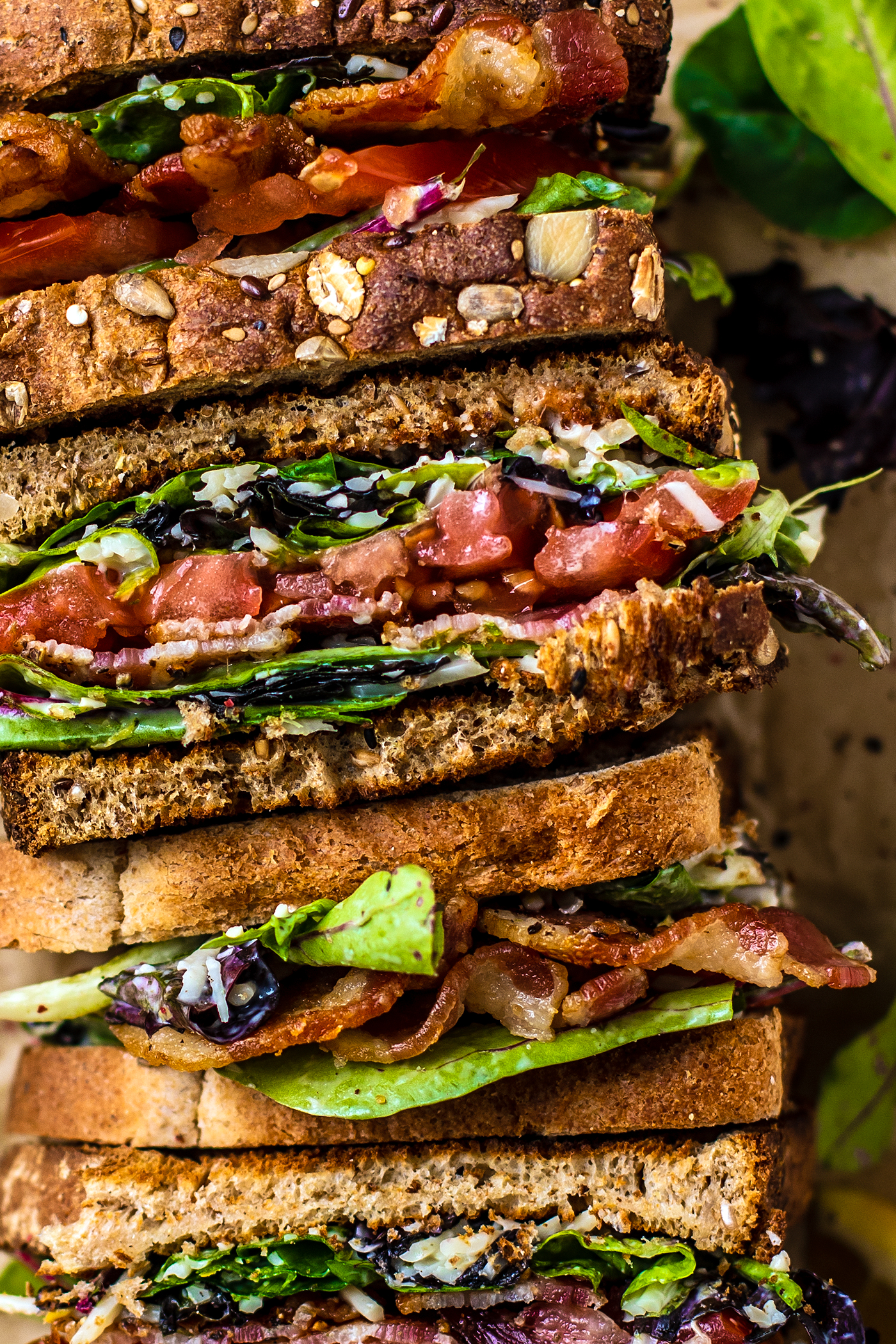 Close up of BLT sandwiches stacked on a serving platter laying down.