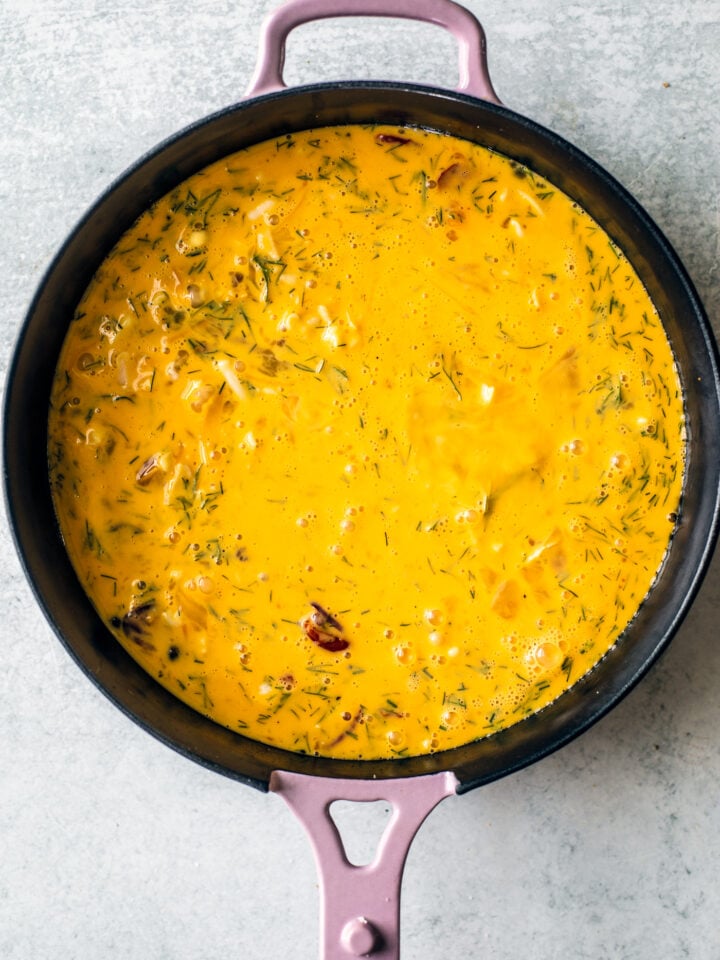 Raw quiche ingredients in cast iron skillet.