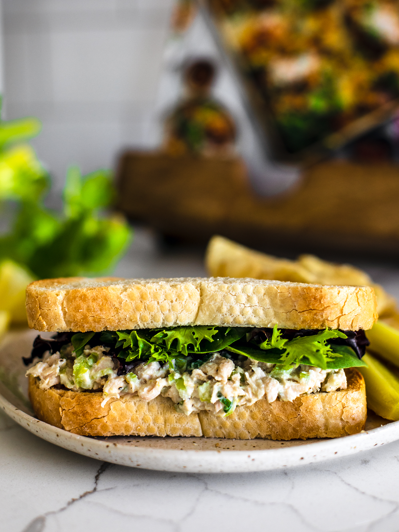 Close up of a tuna sandwich with lettuce on white kitchen counter.
