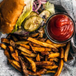 Burger and fries in a basket with small container of homemade ketchup.