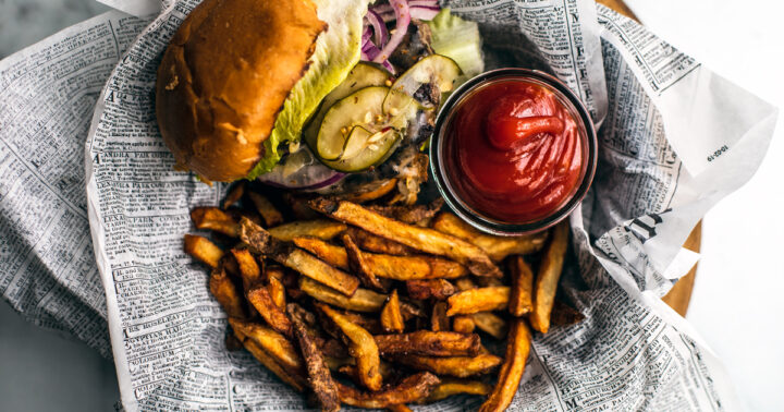 Burger and fries in a basket with small container of homemade ketchup.