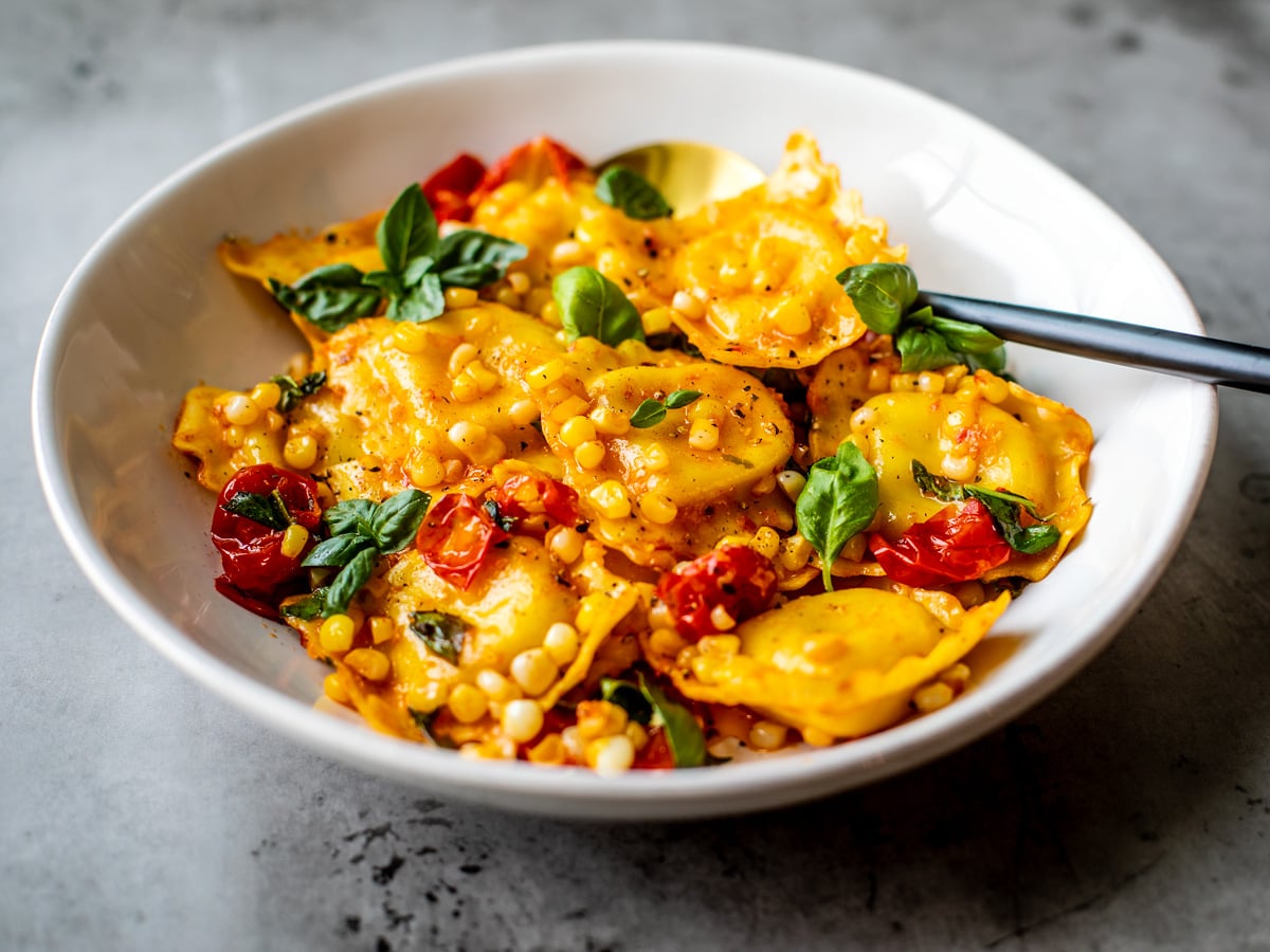 Ravioli and veggies in a serving bowl.