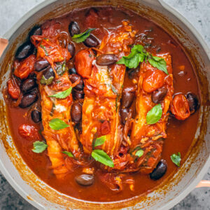 Sauté pan with salmon fillets in tomato and red wine sauce.