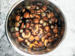 Mushrooms and pearl onions with red wine mixed into the Instant Pot.