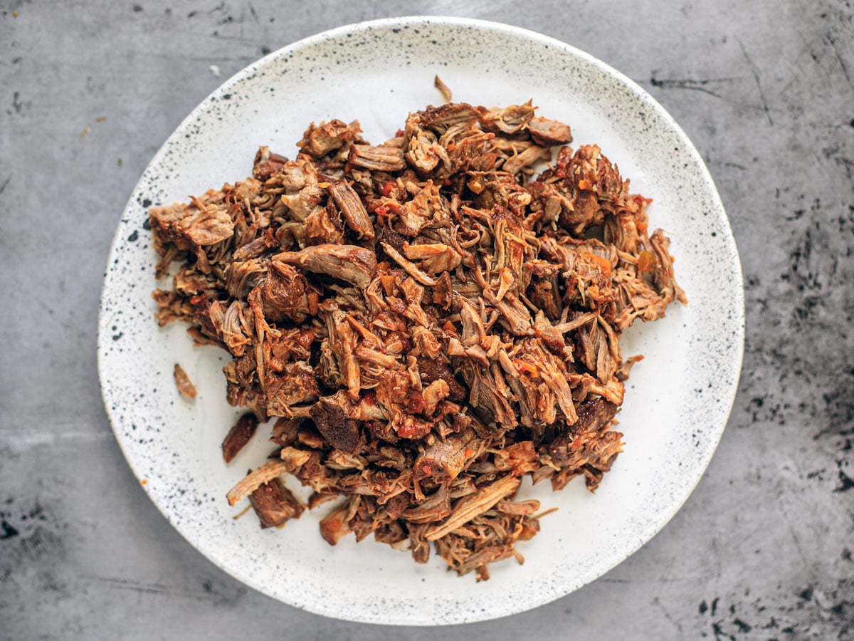 Shredded cooked pork on a white serving plate.