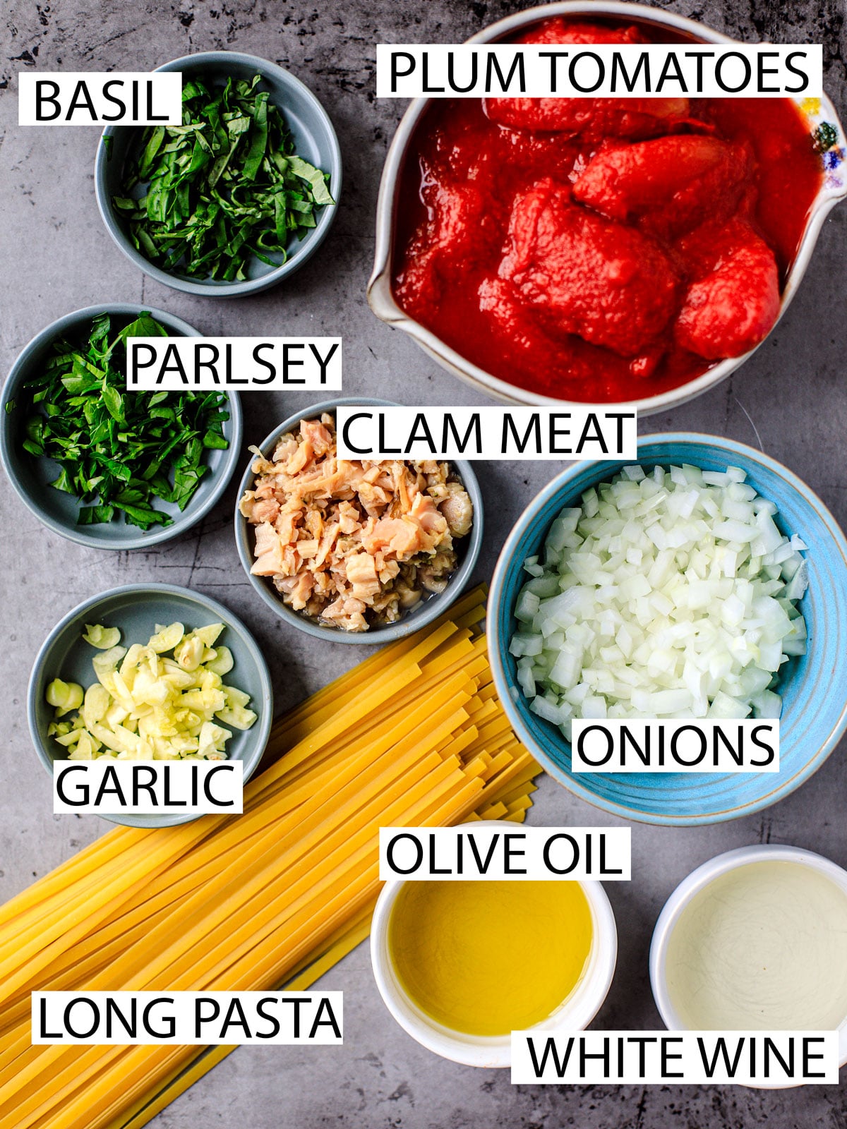 Ingredients for clam pasta in bowls and labelled.