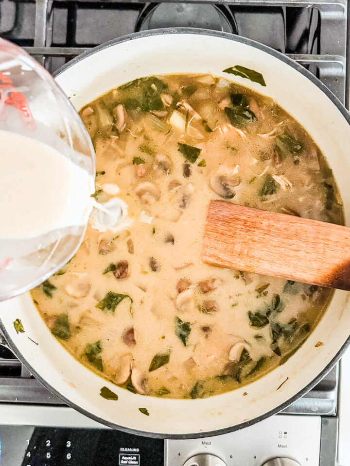 Heavy cream being added to the pot of soup.