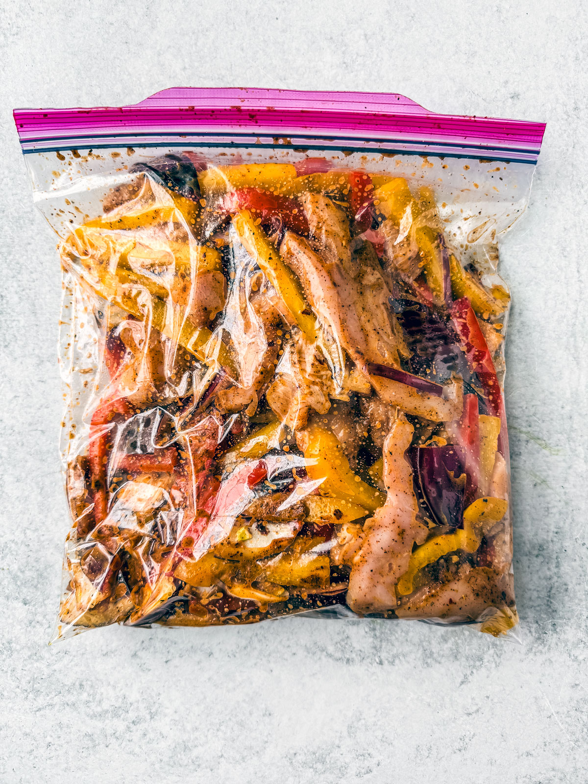 Gallon zip-top bag full of marinated chicken fajita ingredients.