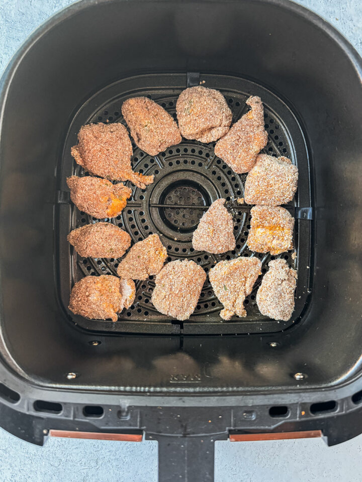 Air fryer basket with uncooked nuggets in it.
