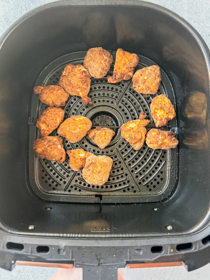 Air fryer basket with cooked nuggets in it, golden and crispy.