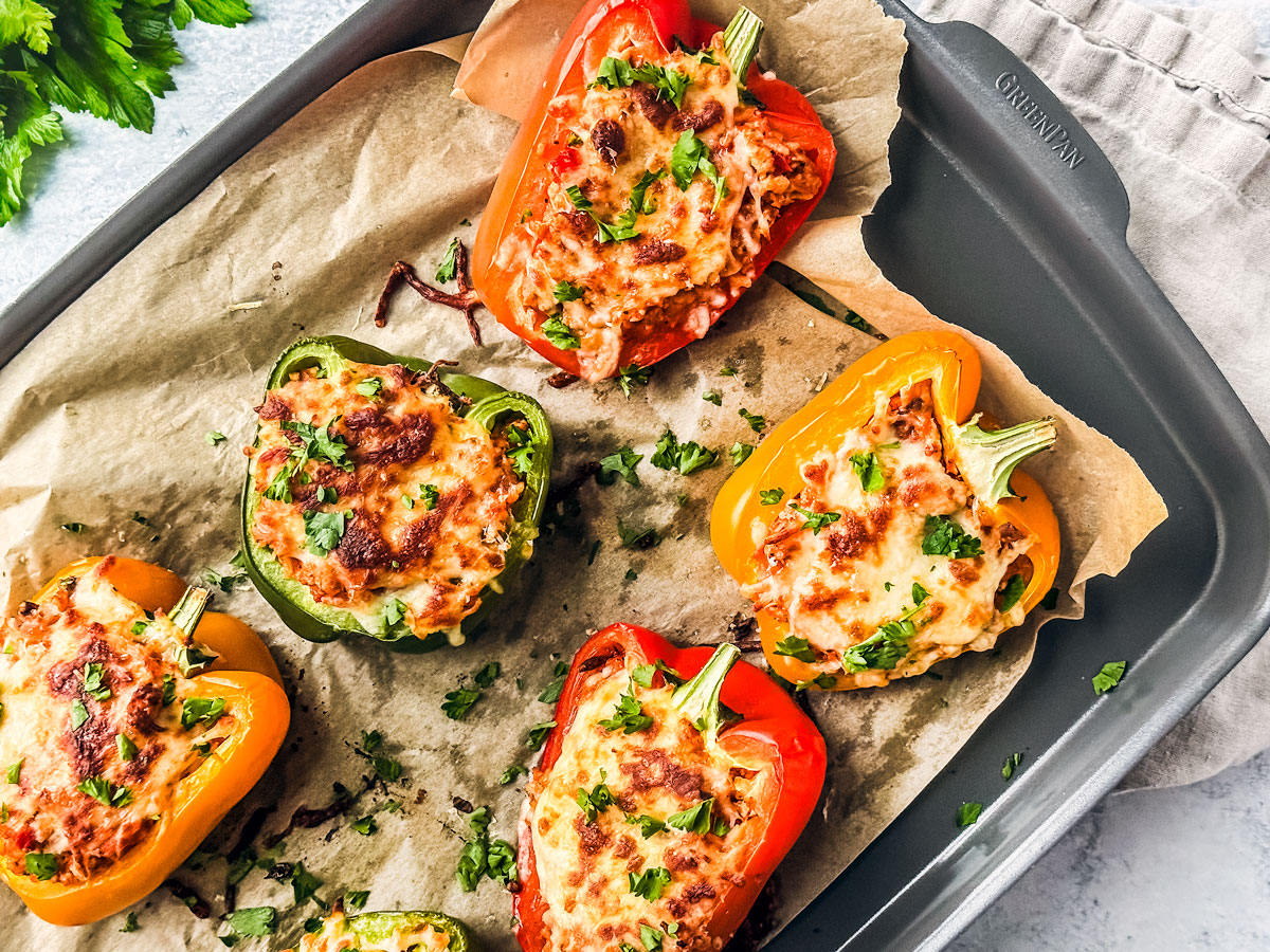 Baked stuffed peppers with ground turkey on a baking sheet with parchment paper.