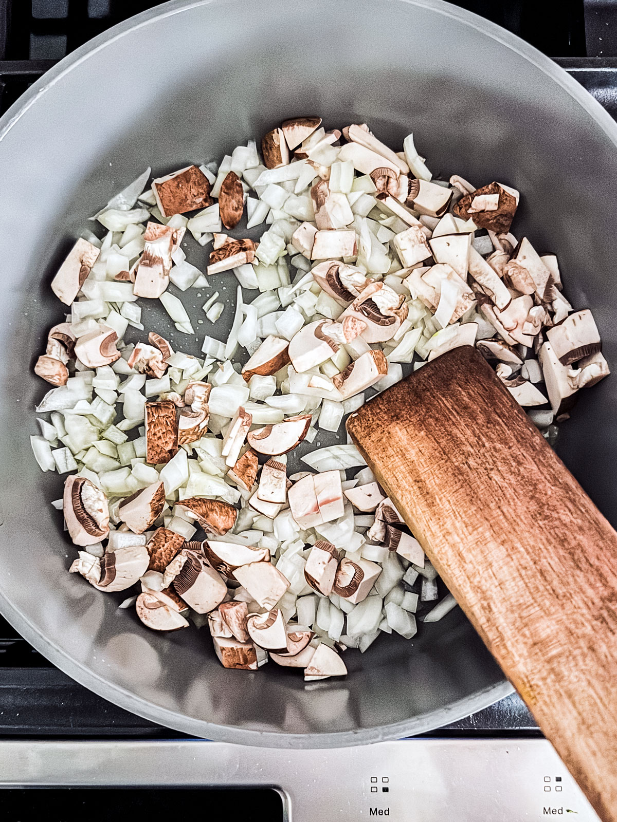 Onions and mushrooms being cooked in a skillet.