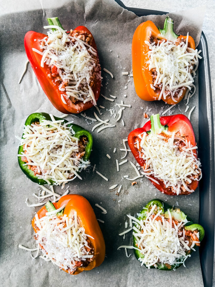 Peppers stuffed and topped with cheese prior to baking.