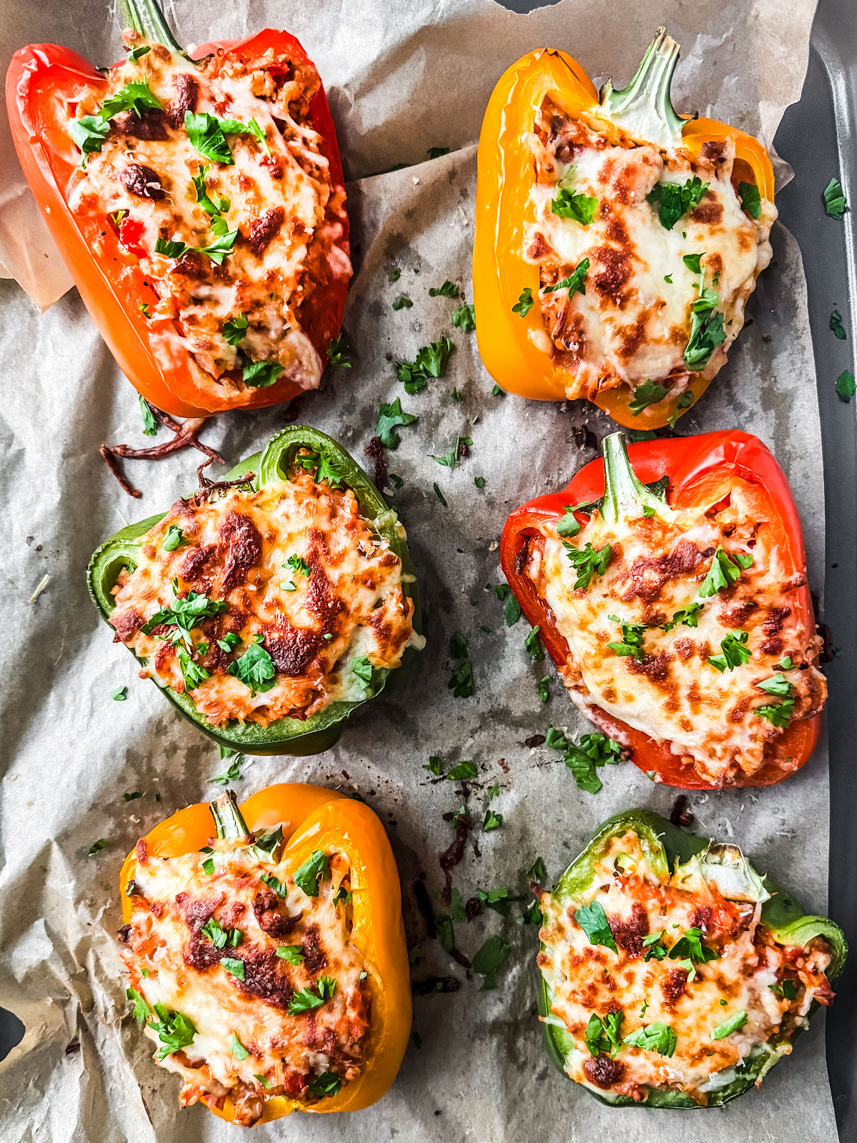Baked cheesy stuffed peppers with ground turkey garnished with fresh parsley.