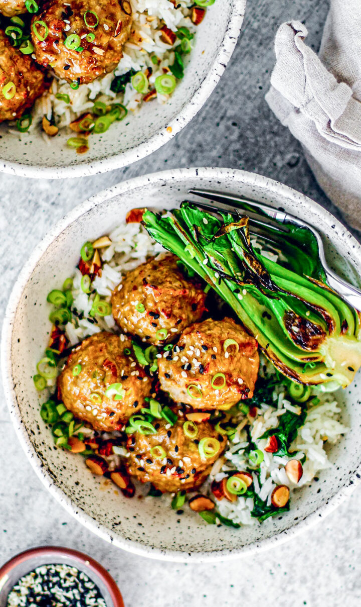 Ginger garlic meatballs with hot honey glaze on a bed of rice in a bowl.
