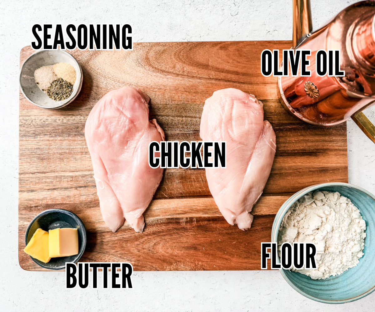 Chicken breasts on a cutting board with dishes of butter, flour, seasoning, and olive oil around it.