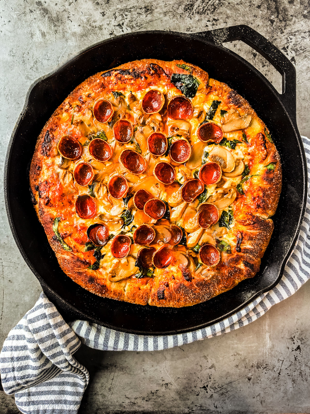 Pepperoni, spinach, and mushroom pizza in a cast iron pan.