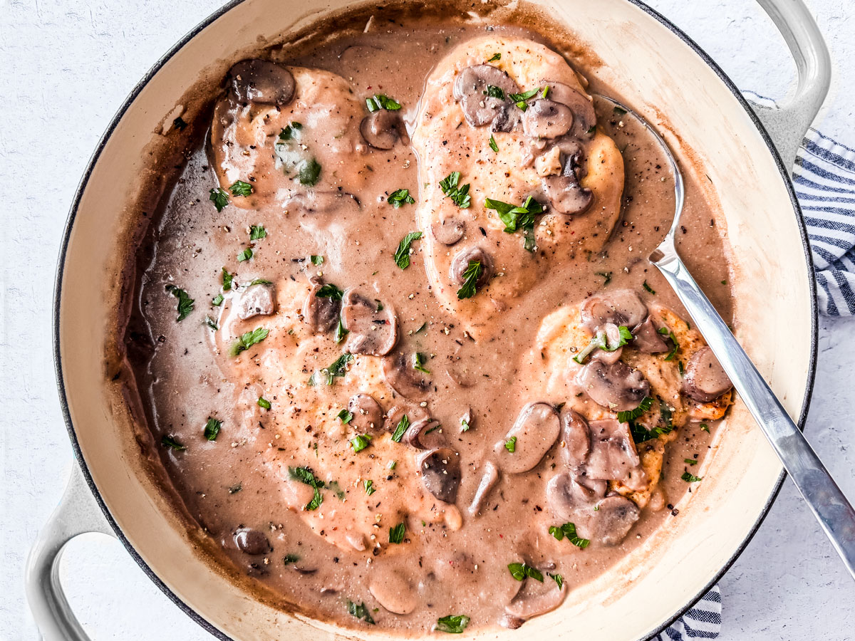 Chicken smothered in creamy mushroom sauce in a skillet.